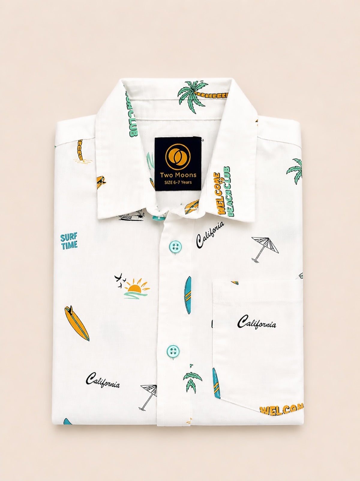 Neatly folded white kids button-down shirt displaying the retro California beach club graphics and contrasting turquoise buttons.