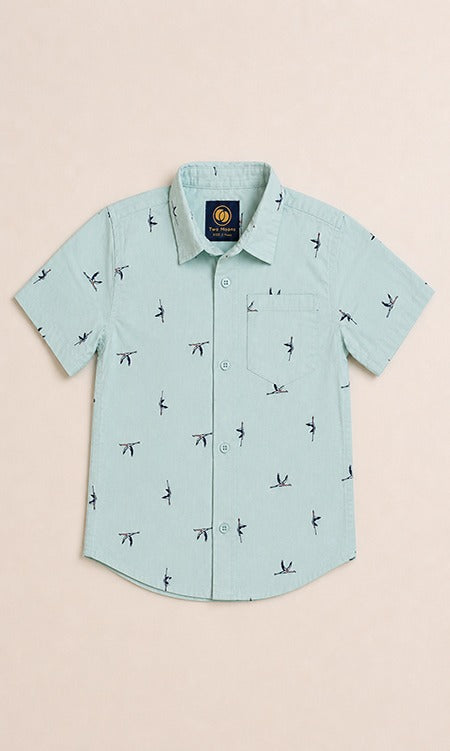 Front view of a light mint green kids short-sleeve button-down shirt featuring a minimalist dark flying bird pattern.