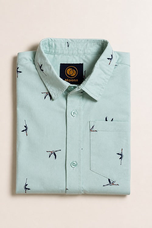 Neatly folded light mint green kids button-down shirt highlighting the minimalist flying bird pattern and matching buttons.
