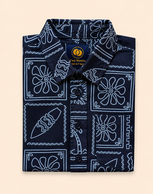 Neatly folded navy blue kids button-down shirt emphasizing the white line-art surfboard and wave print.