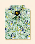 Folded Two Moons Canada kids short-sleeve button-down shirt featuring a cartoon blue dog and tropical green leaves on a mint background.