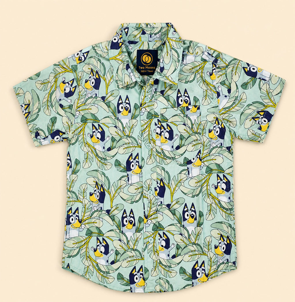 Two Moons Canada kids short-sleeve button-down shirt front side featuring a cartoon blue dog and tropical green leaves on a mint background.