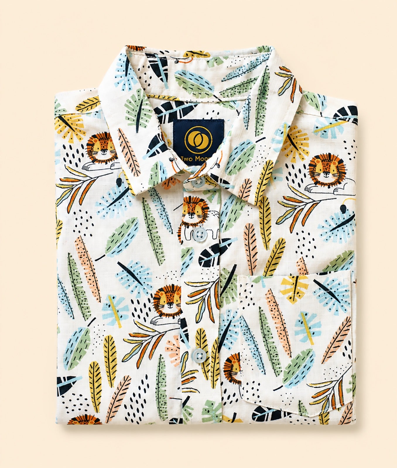 Neatly folded white kids button-down shirt highlighting the colorful safari lion and jungle leaf pattern.