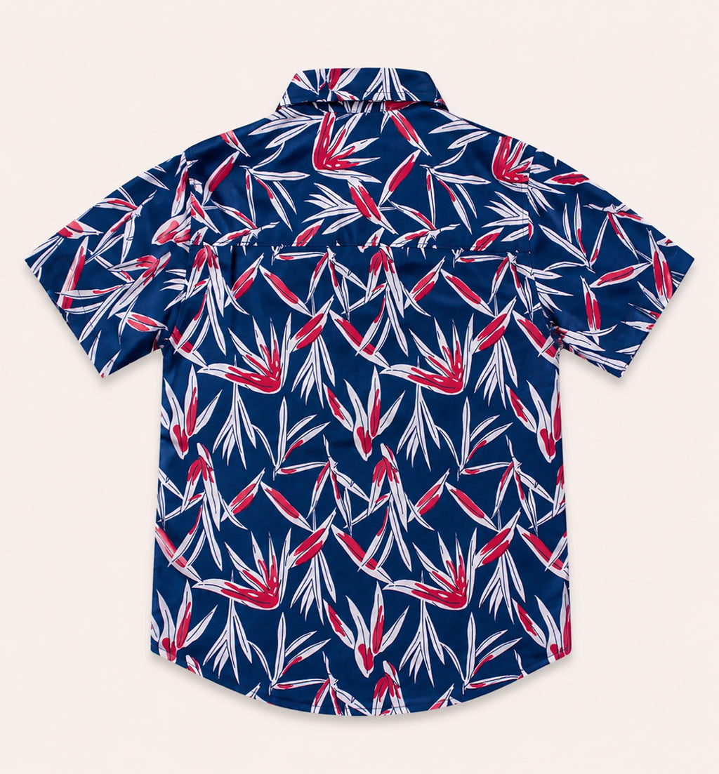 Back view of a navy blue kids short-sleeve button-down shirt showcasing the high-contrast red and white tropical leaf pattern.