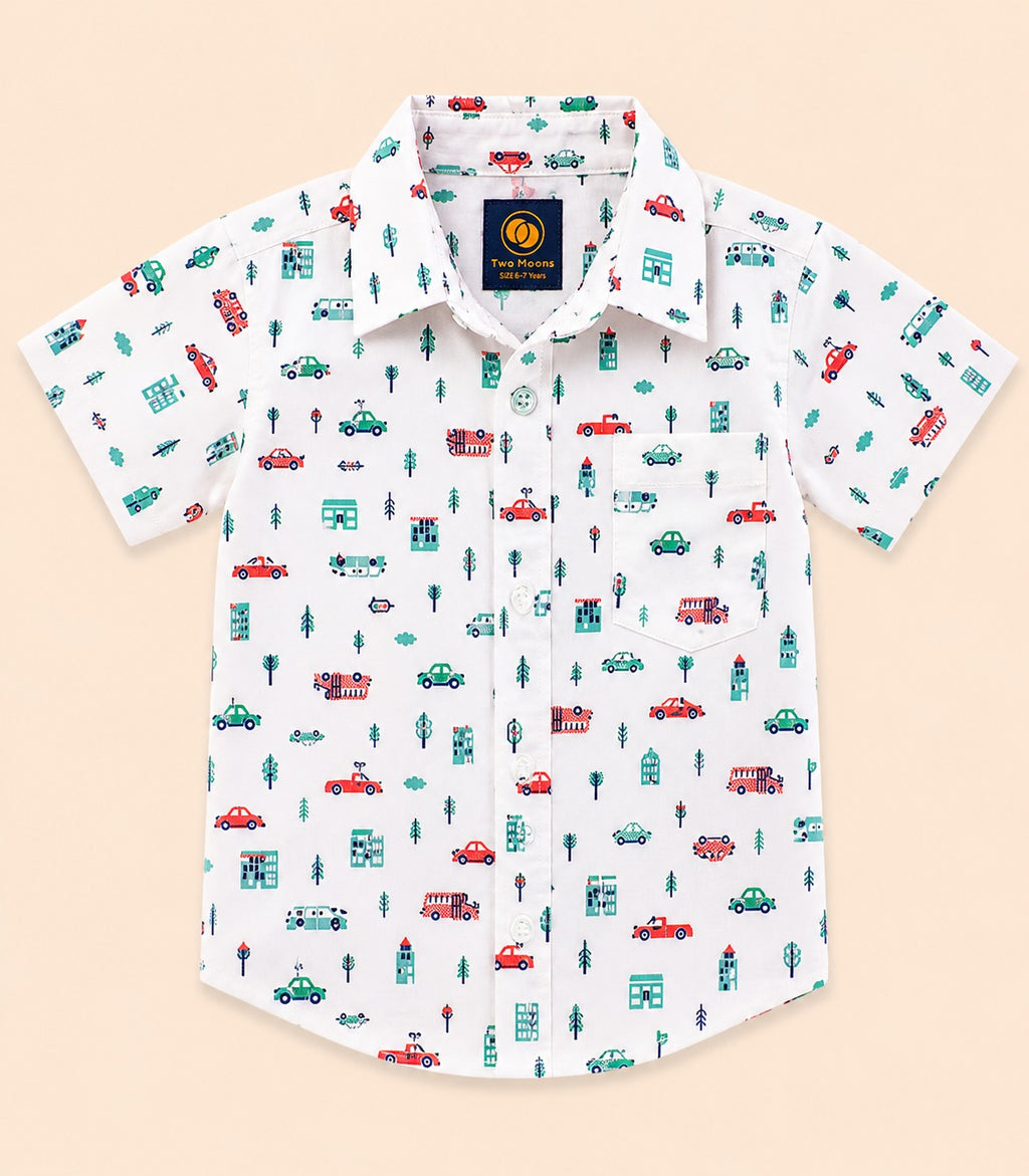 Front view of a white kids short-sleeve button-down shirt featuring a colorful town print with cars, buses, buildings, and trees.