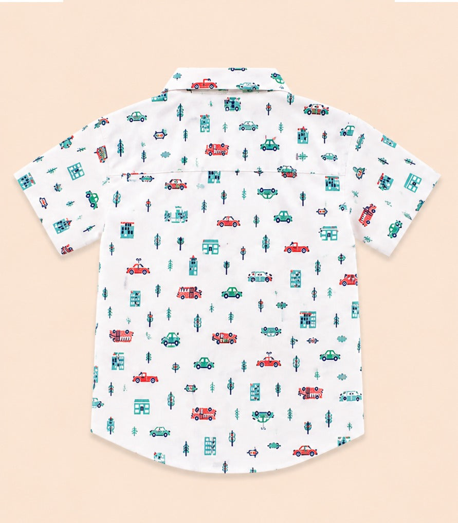 Back view of a white kids short-sleeve button-down shirt showcasing the repeating playful traffic and city pattern.