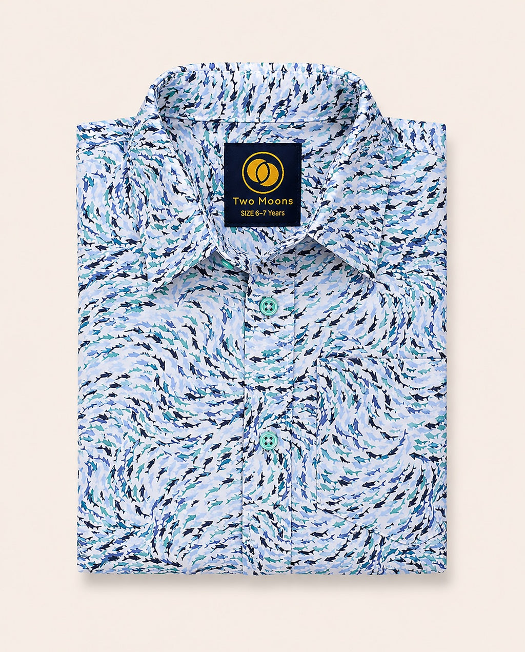 Neatly folded kids button-down shirt highlighting the swirling blue abstract wave print and contrasting light teal buttons.