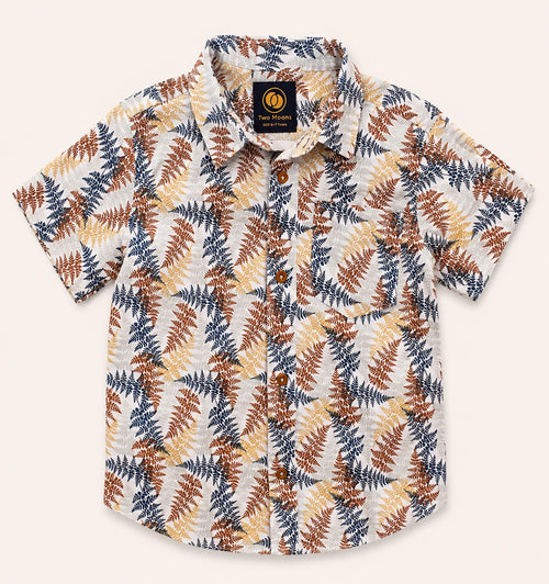 Front view of a cream kids short-sleeve button-down shirt featuring an earthy rust, yellow, and navy botanical fern print.