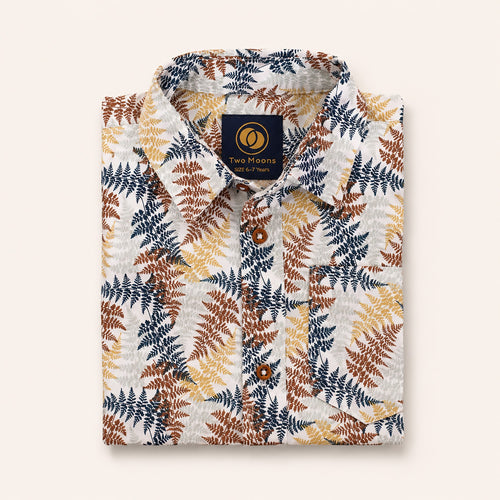 Neatly folded cream kids button-down shirt highlighting the rust and navy fern leaf print and classic wood-style buttons.